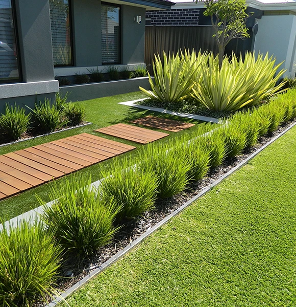 Modern garden with neatly trimmed grass, wooden stepping stones, and lush green plants alongside a house. Clean, organized, and serene.